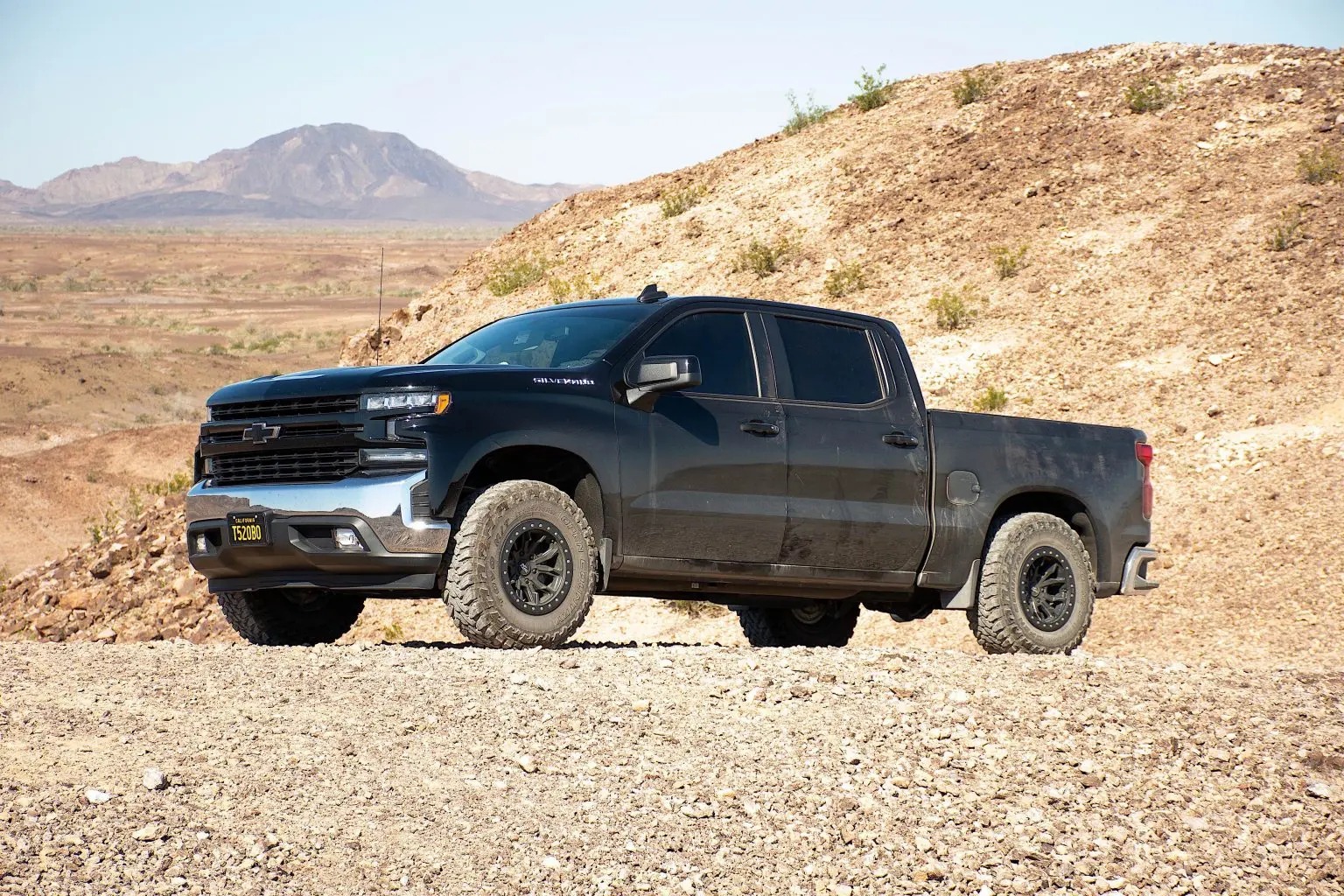 A black Chevrolet truck on a rocky road.