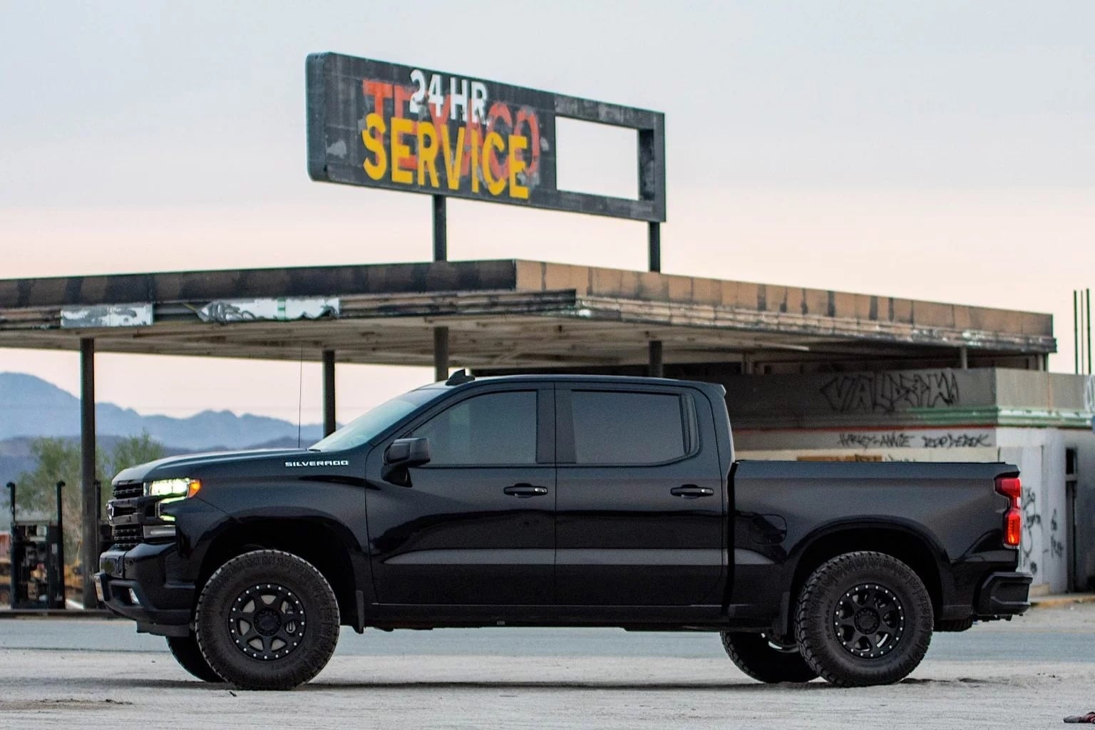 2019 Chevrolet Silverado in front of a service station sign.