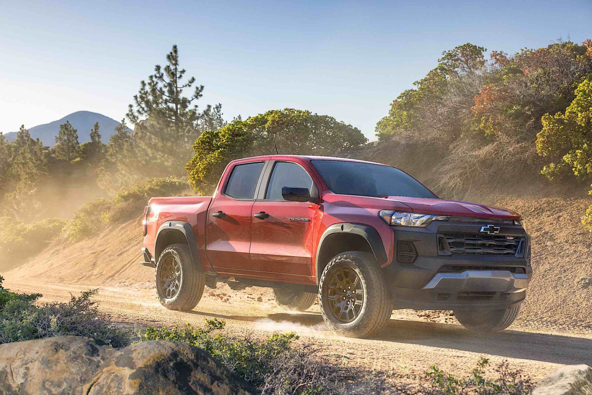 A Red 2023 Chevrolet Colorado driving down a dirt road.