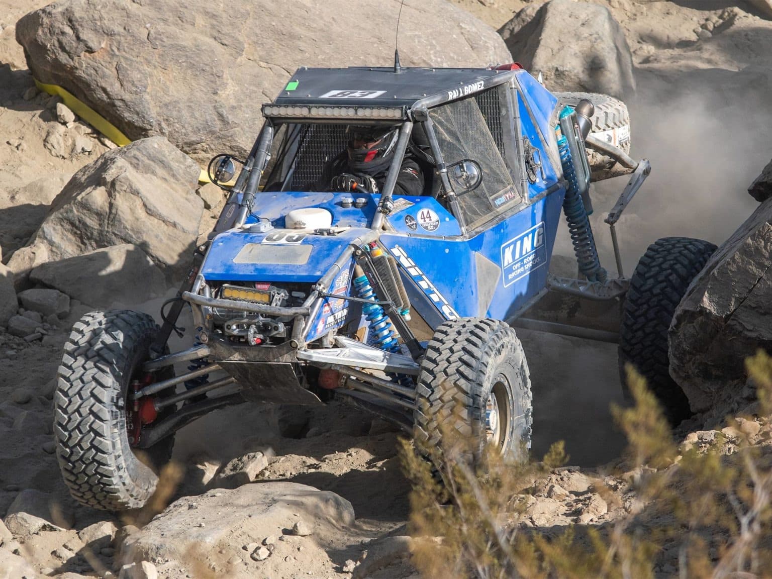 A blue off-road vehicle traversing over rocky, difficult terrain.